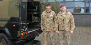 Army officers standing beside Land Rover Defender during trip to College.