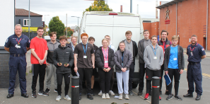Public and Uniformed Services students stand in front of the Navy's van during their visit, alongside officers Garner and Wignall.