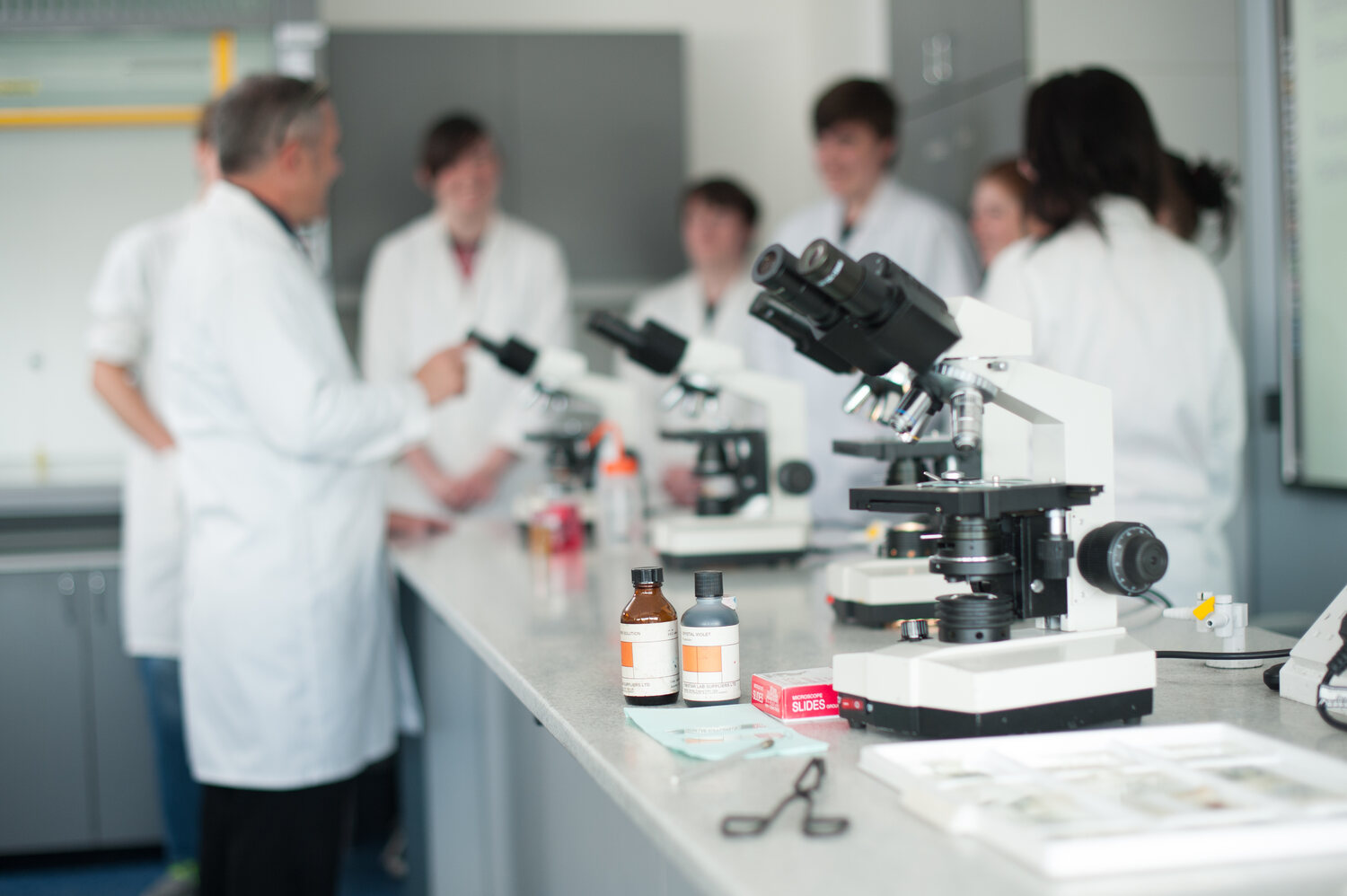 science students with teacher amongst microscopes