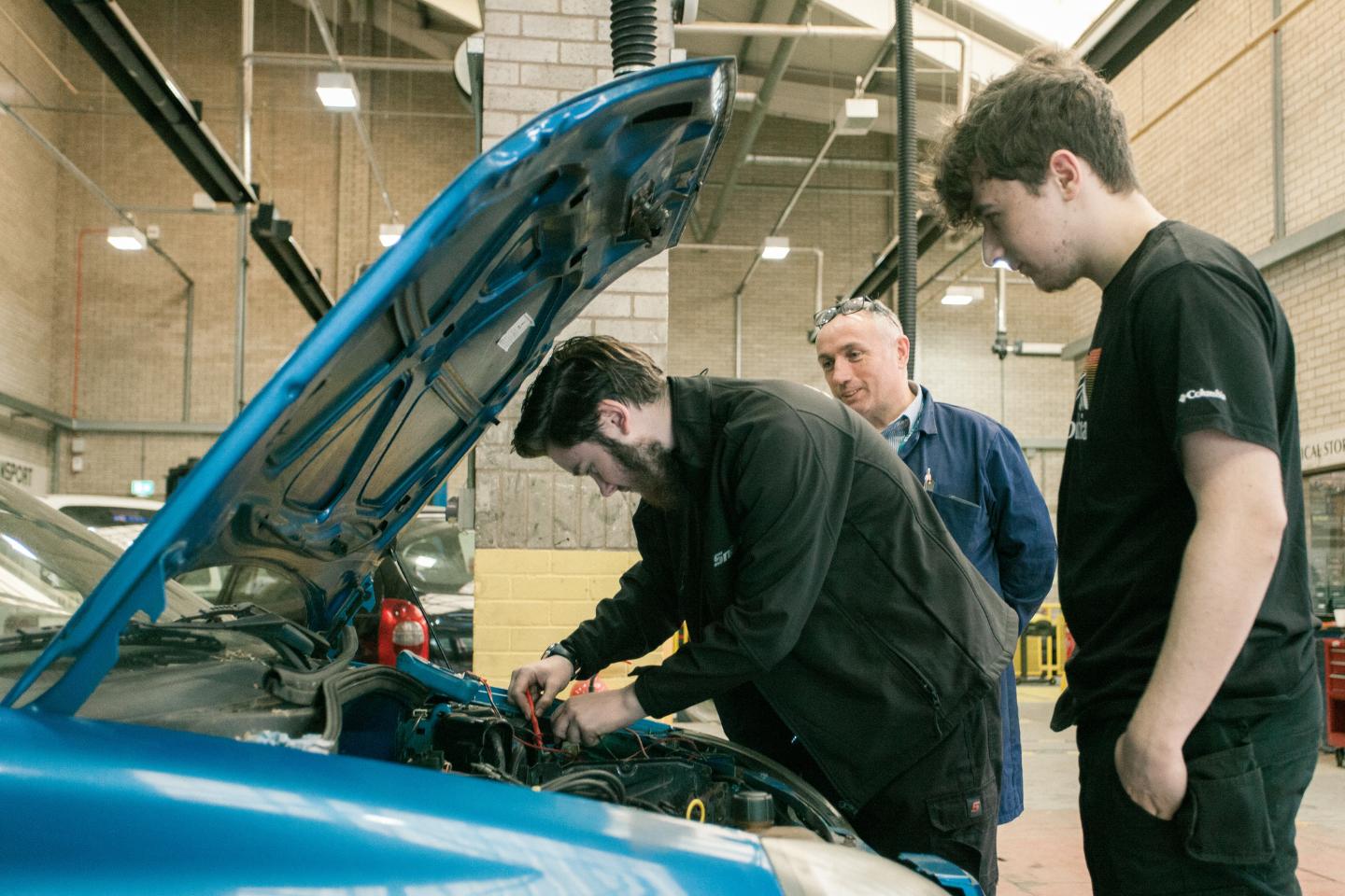 Student underneath the bonnet of a car