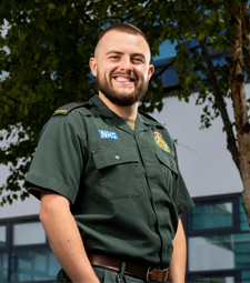 Access to HE student wearing his North West Ambulance Service uniform and smiling