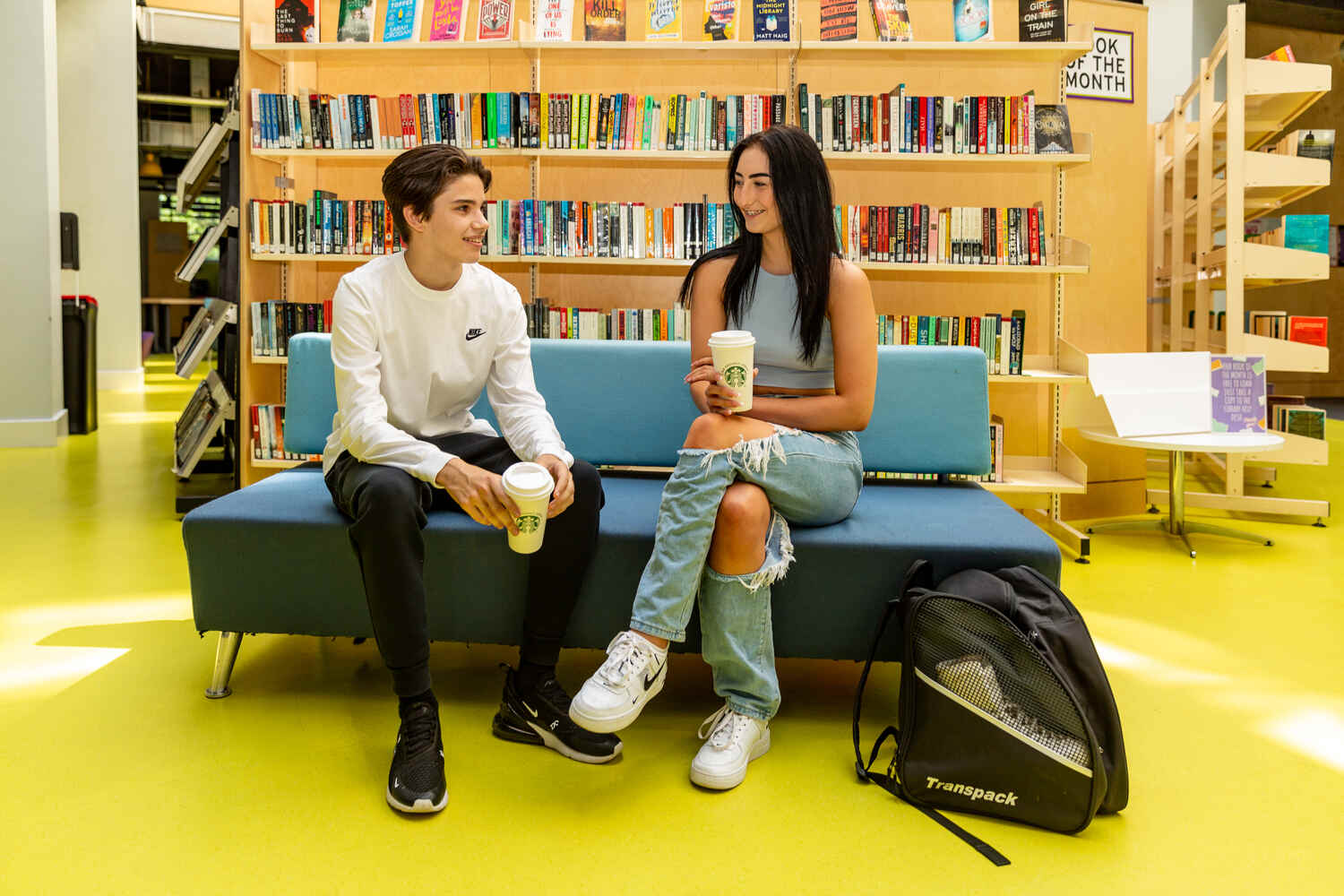 two students sat together in a library with starbucks cups