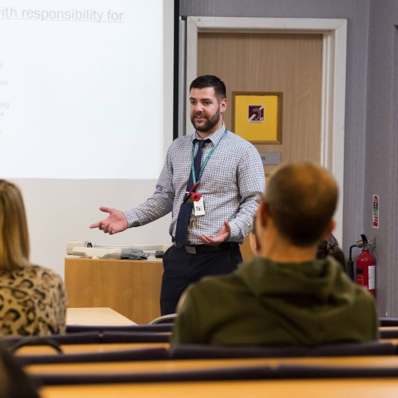 teacher stood in front of whiteboard with his students looking at him